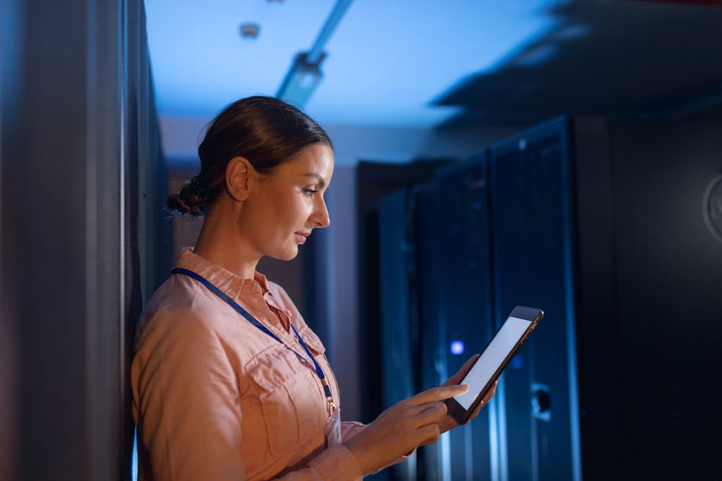 Caucasian female engineer using digital tablet in computer server room