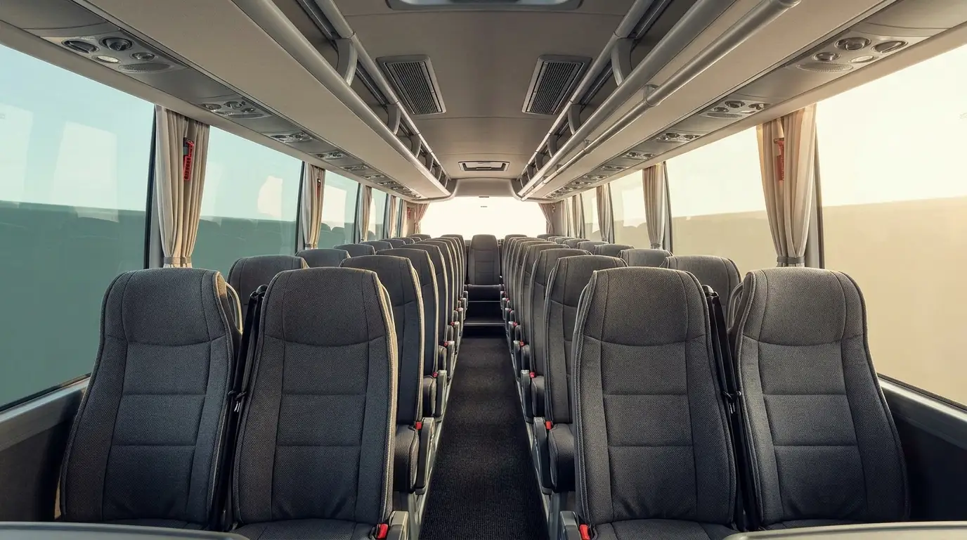 Coach bus interior with reclining high-back seats, overhead luggage racks, and individual reading lights